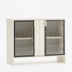 Lav skjenk med to glassdører og midtplassert håndtak i lys beige – LAYERS-kolleksjonen.